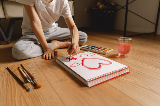 Boy drawing a valentine card with hearts for Valentine's Day