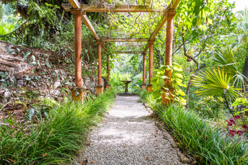 Gazebo perspective with fountain in romantic garden. Green idyllic landscaped patio.