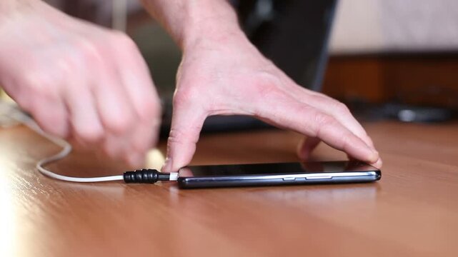 A man connects a dead mobile phone to a Type-C charger.