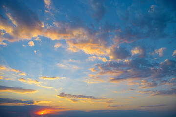 Vibrant sunset sky with colorful clouds glowing in orange yellow pink blue hues at the horizon...