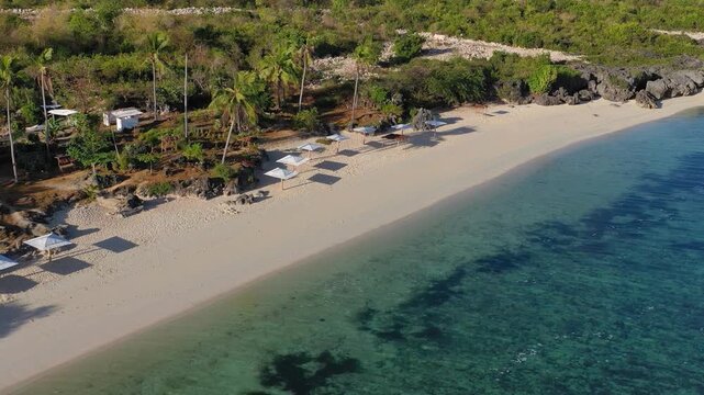 Aerial view of sandy tropical beach with sunbeds and umbrellas
