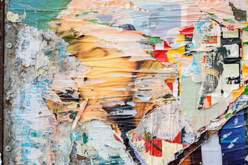 Fototapeta premium Abstract torn paper collage with layered posters and peeling paint forming colorful textured surface. Urban creativity, raw artistic background