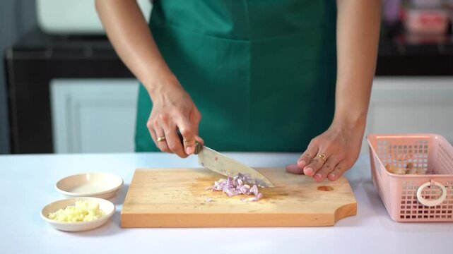 Close up of hands mincing red onions on wooden board