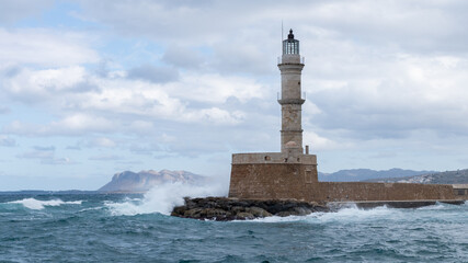 Chania lighthouse with waves crashing on stone pier, Crete