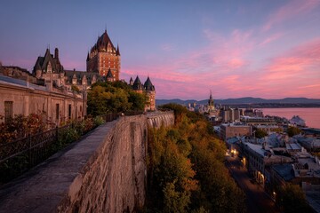 Fototapeta premium Picturesque cityscape at dusk features a historic castle atop a hill overlooking the city and river