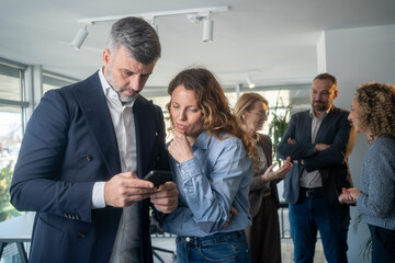 Obraz premium Businessman reviewing business data with female colleague on phone during break