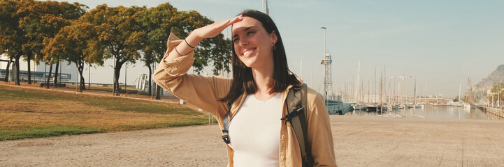 Traveler girl, with backpack on her shoulders, walks in the port of European city. Panoramic....