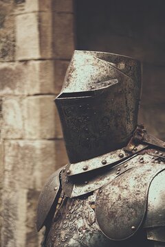 Medieval knight in steel armor against the background of castle walls. The medieval knight stands firmly against the backdrop of the castle, ready to defend his honor and people.