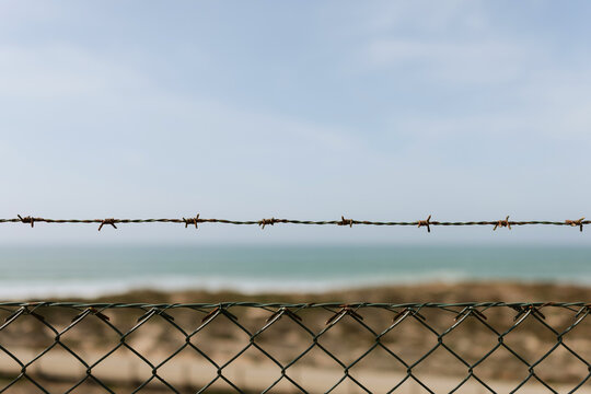 Barbed wire fence against a coastal landscape