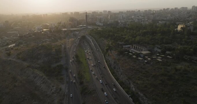 Aerial view of the bustling highway with vehicles, cutting through Yerevan's landscape, contrasting with the city buildings and lush greenery, Yerevan, Yerevan, Armenia.