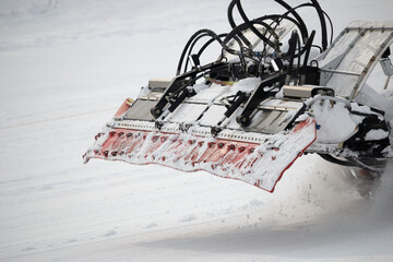 Rear of vehicle grooming snow on ski piste in winter