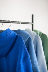 Obraz premium Various hoodies hanging on a rack in a simple indoor setting during daylight hours