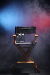 Film director's chair and clapperboard on dark background in neon lights with smoke