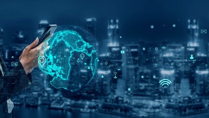 A modern city skyline illuminated at night serves as the backdrop for a hand holding a smartphone,...