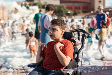 Child with cerebral palsy enjoying foam party in wheelchair