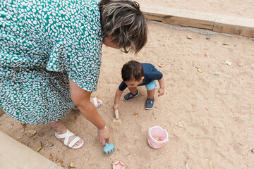 mother and grandson playing together in sandbox