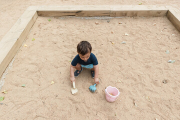 Toddler boy playing with sand toys in sandbox