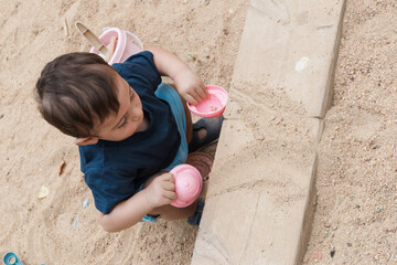 Toddler boy playing with sand in sandbox outdoors