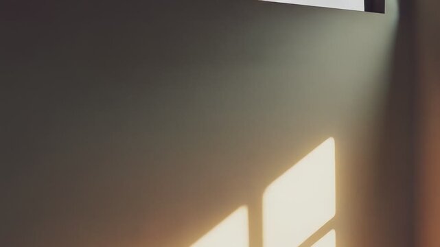 Warm sunlight illuminating an empty room, creating abstract window shadows and light patterns across the beige wall and floor, reflecting a peaceful and tranquil atmosphere, ideal for background
