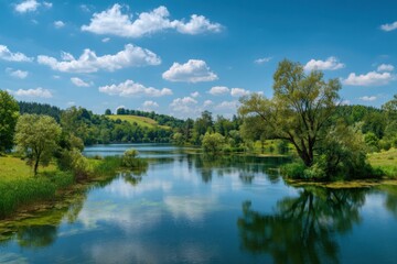 Peaceful lake surrounded by lush greenery under a blue sky filled with fluffy clouds on a bright sunny day in the countryside