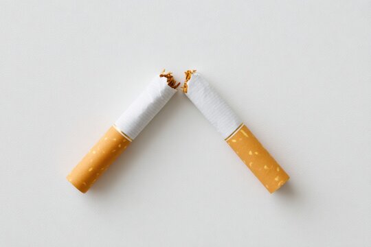 Broken cigarette placed on a clean surface, showcasing the torn filter and exposed tobacco, emphasizing the act of quitting smoking and its health implications