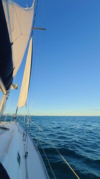 Valencia sailboat at sunset cruising on Mediterranean sea with golden light