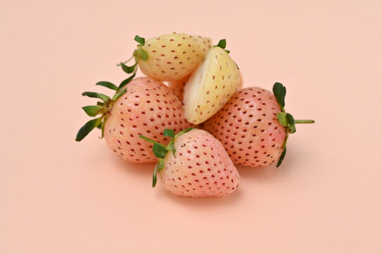 a bunch of ripe pineberries on a pink background close-up