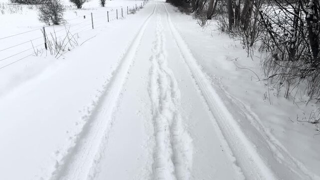 Snowy village road with car and foot tracks