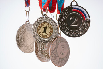 A collection of medals and ribbons, including a silver one with a number 2 on it. The medals are hanging from a string, and the ribbon is blue and red