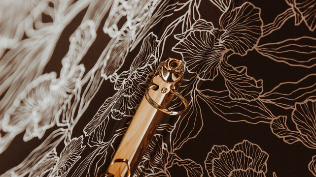 Open binder with gold metal clasp and leaf-patterned black and white interior design