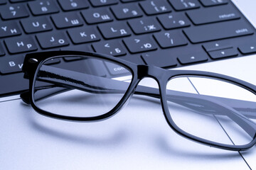black-rimmed glasses for vision on a laptop keyboard. High quality photo