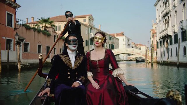 Romantic couple wearing traditional Venetian carnival masks riding a gondola through canals of Venice, Italy. Cinematic travel scene, luxury tourism and European culture
