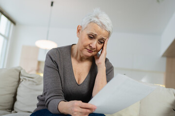 Sad tired ill sick lonely disappointed older senior woman reading bad news at home alone. Unhappy...