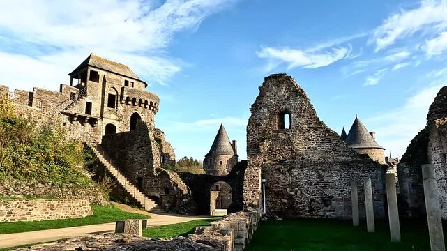 Historic castle ruins with stone walls under blue sky. Fougères Castle, Brittany, France.
  