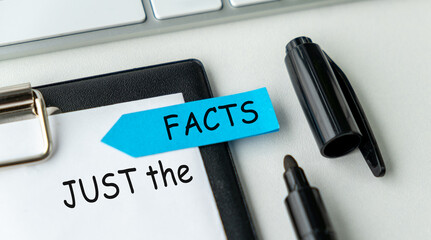 Text JUST THE FACTS on the white paper on clipboard with chart and marker
