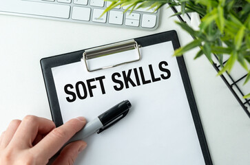 A hand holding a piece of white paper with the text Soft Skills written on it