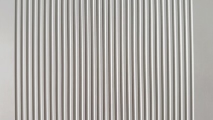 Obraz premium Vertical white ribbed panel texture, clean modern backdrop for product photography with soft shadow lines, subtle groove depth and monochrome architectural surface ideal for branding mockups