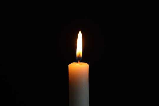 Holocaust Remembrance Day. Burning candle against black background, closeup