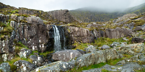 Waterfall at the Conor Pass, one of the highest Irish mountain passes served by an asphalted road, located on the south-western end of the Dingle Peninsula, County Kerry, Ireland