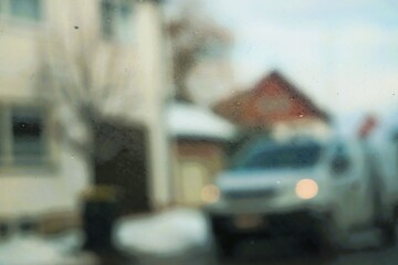 Abstraktes Motiv mit um die Kurve fahrendem silbernem Pick-up mit Licht vor Einfamilienh&auml;usern und Schneebedecktem Gehweg in Dorf bei Sonne, Eis und Frost am Nachmittag im Winter