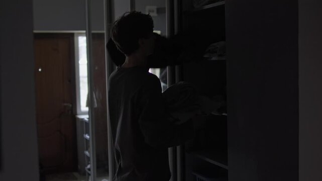 Man taking clothes from wardrobe. Decluttering, minimalism and home organization concept. Simple living, clean space, lifestyle routine, modern apartment.