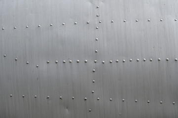 Symmetrical rivet grid on metal surface with matte stripes and repeating fasteners, aircraft skins,...