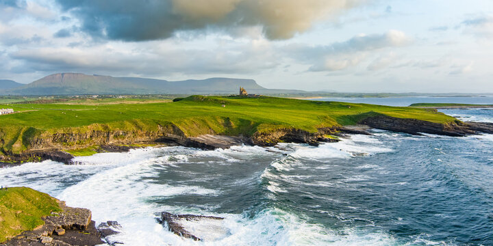 Famous Classiebawn Castle in picturesque landscape of Mullaghmore Head. Spectacular sunset view with waves rolling ashore. Signature point of Wild Atlantic Way, Co. Sligo, Ireland