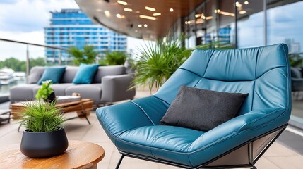 Fototapeta premium A blue leather chair with a black pillow on it sits on a balcony overlooking a city. The chair is surrounded by potted plants and a table with a vase on it. Concept of relaxation and luxury