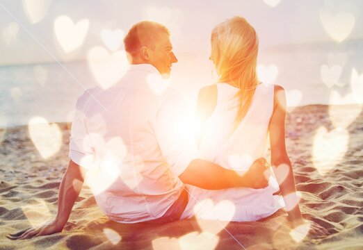 Happy couple sitting on beach at sunrise