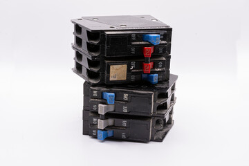 Two old burnt out and damaged electrical breakers stacked up on a white background. 