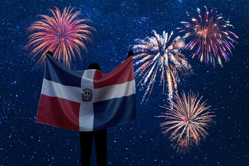 Girl holds in hands National flag of Dominican Republic on Independence day and fireworks