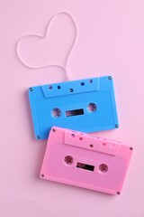 Obraz premium Music cassettes and heart made with tape on pink background, top view