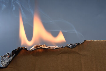a piece of cardboard burning on a gray background