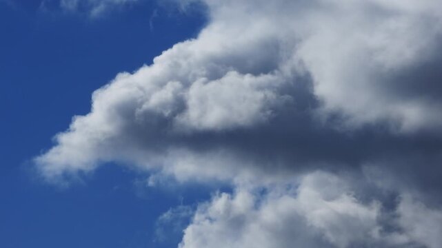 Zoom cinematic timelapse video of white cloud formations on a windy day in deep blue sky
